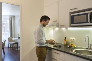 un homme debout dans une cuisine préparant la nourriture dans l'établissement Citadines Castellane Marseille, à Marseille