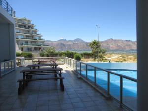 two benches sitting on a balcony next to a swimming pool at Tranquil Impulse on Strand in Cape Town