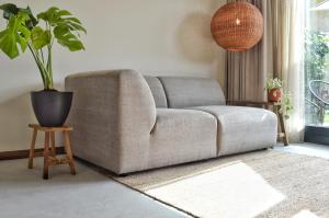 un salon avec un canapé et une plante en pot dans l'établissement Van Heeckeren Apartments & Suites Nes, à Nes