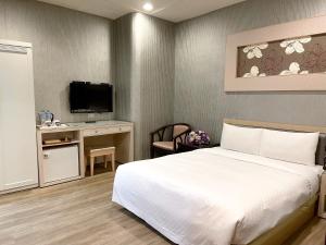 a bedroom with a bed and a desk with a tv at Beidoo Hotel in Keelung