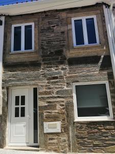 Una casa de ladrillo con dos ventanas y una puerta en Casa da Muralha, en Vila Nova de Foz Cõa