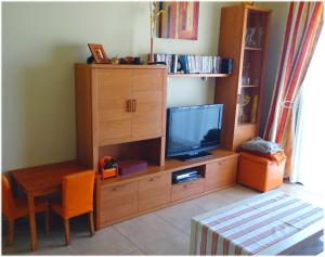 ein Zimmer mit einem Entertainment-Center mit einem TV und einem Tisch in der Unterkunft Ático Residencial Los Patios, Playa Médano, zona windsurf in El Médano