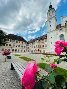 ein Gebäude mit einem Uhrturm und rosa Rosen in der Unterkunft Bischöfliches Seminar St. Willibald in Eichstätt