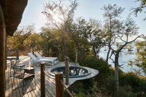 a deck with a hot tub next to the water at Victoria Falls River Lodge in Victoria Falls