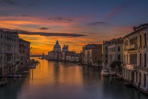 uma vista para um rio com edifícios e um pôr-do-sol em Albergo Casa Peron em Veneza