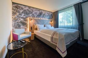 ein Hotelzimmer mit einem Bett und einem Stuhl in der Unterkunft FourSide Hotel Salzburg in Salzburg