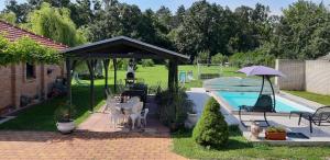 a pavilion with a table and umbrella next to a pool at Penzion Večerka in Lednice