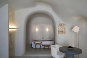 Un dormitorio con una cama y una mesa y sillas. en Elysian Santorini, en Oia