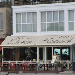a restaurant with tables and chairs in front of a building at Le Continental in Cancale