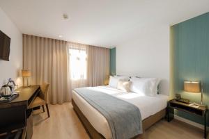 a hotel room with a large bed and a desk at SDivine Fatima Hotel, Congress & Spirituality in Fátima