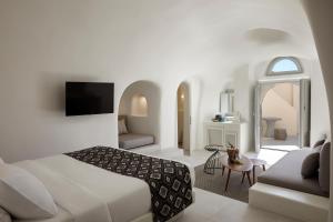 una habitación de hotel con una cama y un sofá en Elysian Santorini, en Oia