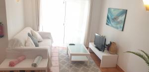 a living room with a white couch and a tv at Apartment Vila Mós in Porto Mós Beach in Lagos