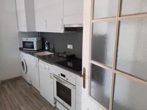 Una cocina con gabinetes blancos y un horno de estufa. en Apartament Ornis Mascarell Vista Alegre, en Sant Carles de la Ràpita