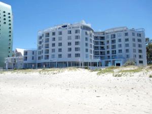 a building on the beach next to a sandy beach at Tranquil Impulse on Strand in Cape Town