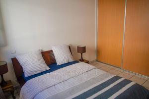 um quarto com uma cama com duas almofadas em Le Géranium: T3 avec vue mer exceptionnelle em Saint-Denis