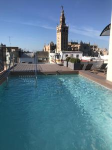 
a large building with a swimming pool and a clock tower at Joya del Casco Boutique Hotel by Shiadu in Seville
