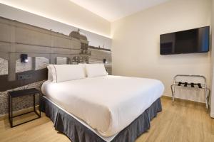 a bedroom with a large white bed and a flat screen tv at Tandem Pópulo in Cádiz