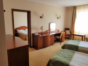 a hotel room with two beds and a desk and a mirror at Hotel Sympozjum & SPA in Krakow