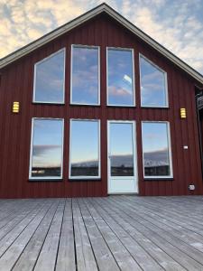 a red building with windows and a wooden deck at Amazing fisherman cabin in the heart of Lofoten in Leknes