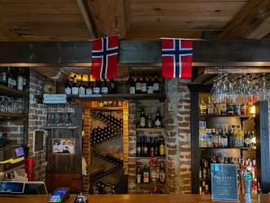 a bar with bottles of alcohol and flags on the wall at Haaheim Gaard in Uggdal
