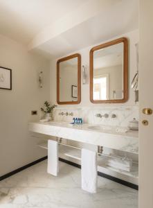 a white bathroom with two sinks and two mirrors at Splendido Mare, A Belmond Hotel, Portofino in Portofino