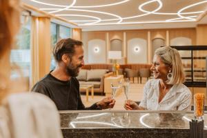 a man and a woman sitting at a counter with wine glasses at Hotel Friesacher in Anif