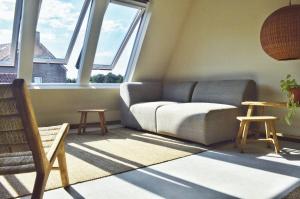 ein Wohnzimmer mit einem Sofa, Tischen und Fenstern in der Unterkunft Van Heeckeren Apartments & Suites Nes in Nes
