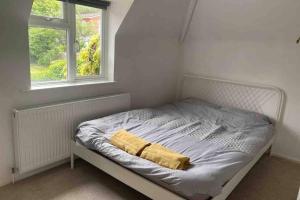 an unmade bed with a yellow blanket and a window at Lovely cottage in the heart of Shirley- Croydon in Shirley