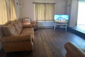 a living room with a couch and a flat screen tv at Lovely cottage in the heart of Shirley- Croydon in Shirley