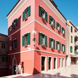 a red building with green shutters on a street at King Kresimir Heritage Hotel in Šibenik