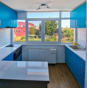 a kitchen with blue cabinets and a large window at Apartament Crina in Jurilovca