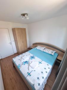 a bedroom with a bed with a blue and white comforter at Apartament Crina in Jurilovca +3 photos