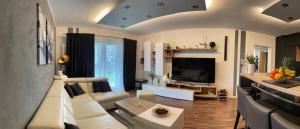 a living room with a white couch and a tv at Krejcarek Garden Apartment in Prague