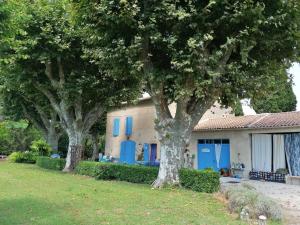 two trees in front of a house with blue doors at Notre campagne provençale in Avignon