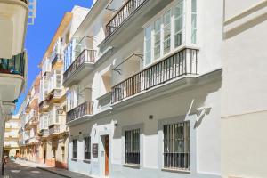 - un bâtiment blanc avec balcon dans une rue dans l'établissement Tandem Pópulo, à Cadix