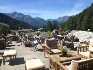 a patio with tables and chairs and a view of mountains at Baita La Jolie Bergere in La Salle