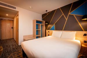 Кровать или кровати в номере ibis Styles Valenciennes Petite Foret