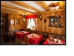 a dining room with two tables with red tablecloths at Baita La Jolie Bergere in La Salle