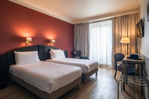 a hotel room with two beds and a red wall at Le Grand Hotel in Strasbourg