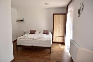 Schlafzimmer mit einem weißen Bett und Holzboden in der Unterkunft Pension U Krbu in Mikulov v Krušných Horách
