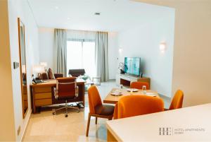 una oficina con sillas naranjas y escritorios en una habitación en HE Hotel Apartments by Gewan, en Dubái