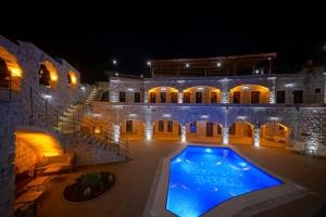 a large stone building with a swimming pool at night at Göreme Cave Lodge in Göreme