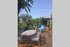 d'une terrasse avec une table, des chaises et une balançoire. dans l'établissement Le Pluie d'Or, à Saint-Louis