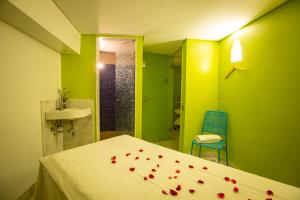 una camera da letto con pareti verdi e un letto con petali di rosa rosso di Hotel Atlantic Agdal a Rabat