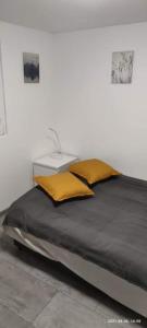 Bett mit gelben Kissen auf einem Zimmer in der Unterkunft Nyíl Apartmanház in Orfű