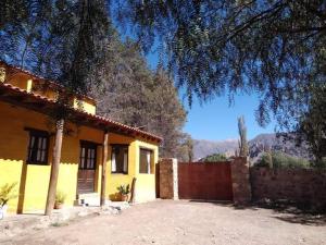 une maison jaune avec une clôture devant elle dans l'établissement La Casa de la Abuela Tilcara, à Tilcara