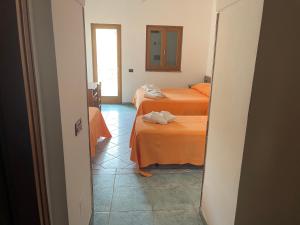 Habitación con 2 camas con sábanas de color naranja y espejo. en Hotel Lo Smeraldo, en Ventotene