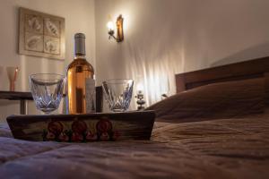 Una botella de vino y dos copas de vino en una cama. en Guesthouse Alexandra, en Eptalofos