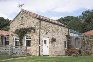 een oud stenen huisje met een witte deur bij Winsbury Cottage in West Hauxwell