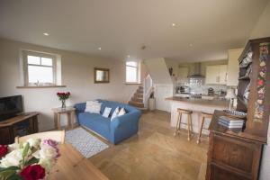 a living room with a blue couch and a kitchen at Winsbury Cottage in West Hauxwell +21 photos